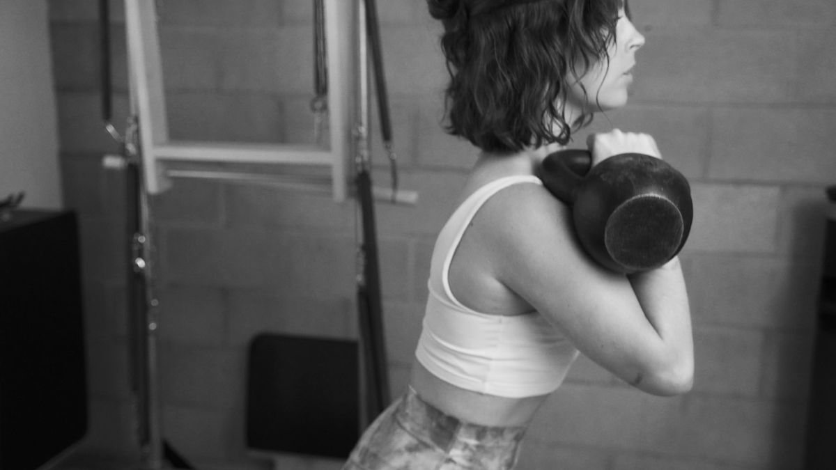 Emphasizing strength and mobility: a motivated woman seamlessly integrating a kettlebell into her Pilates routine at our top-tier West Hollywood Pilates studio, showcasing our commitment to functional movement.