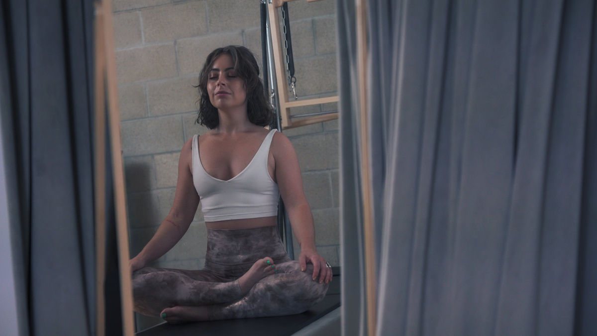 Image of a person practicing Pilates with focused attention and mindfulness, surrounded by serene natural surroundings.
