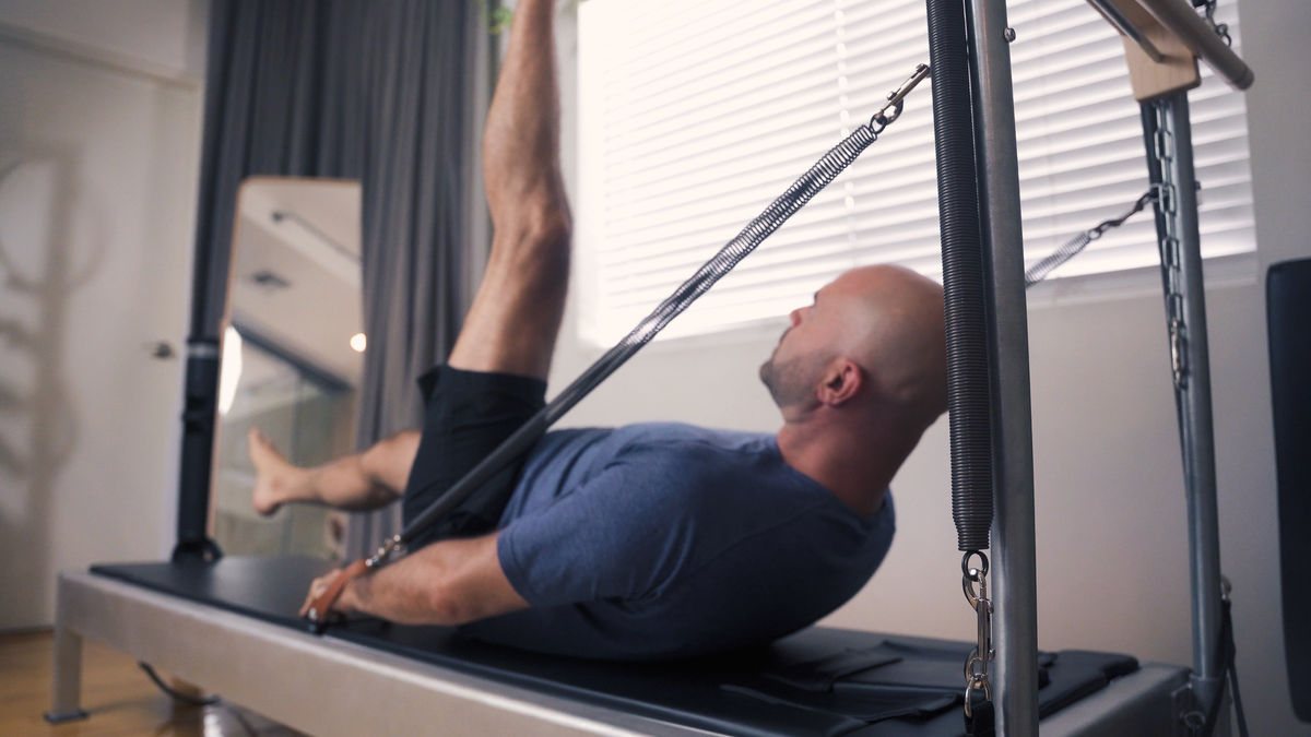 A Pilates practitioner demonstrating a mindful exercise on a reformer.